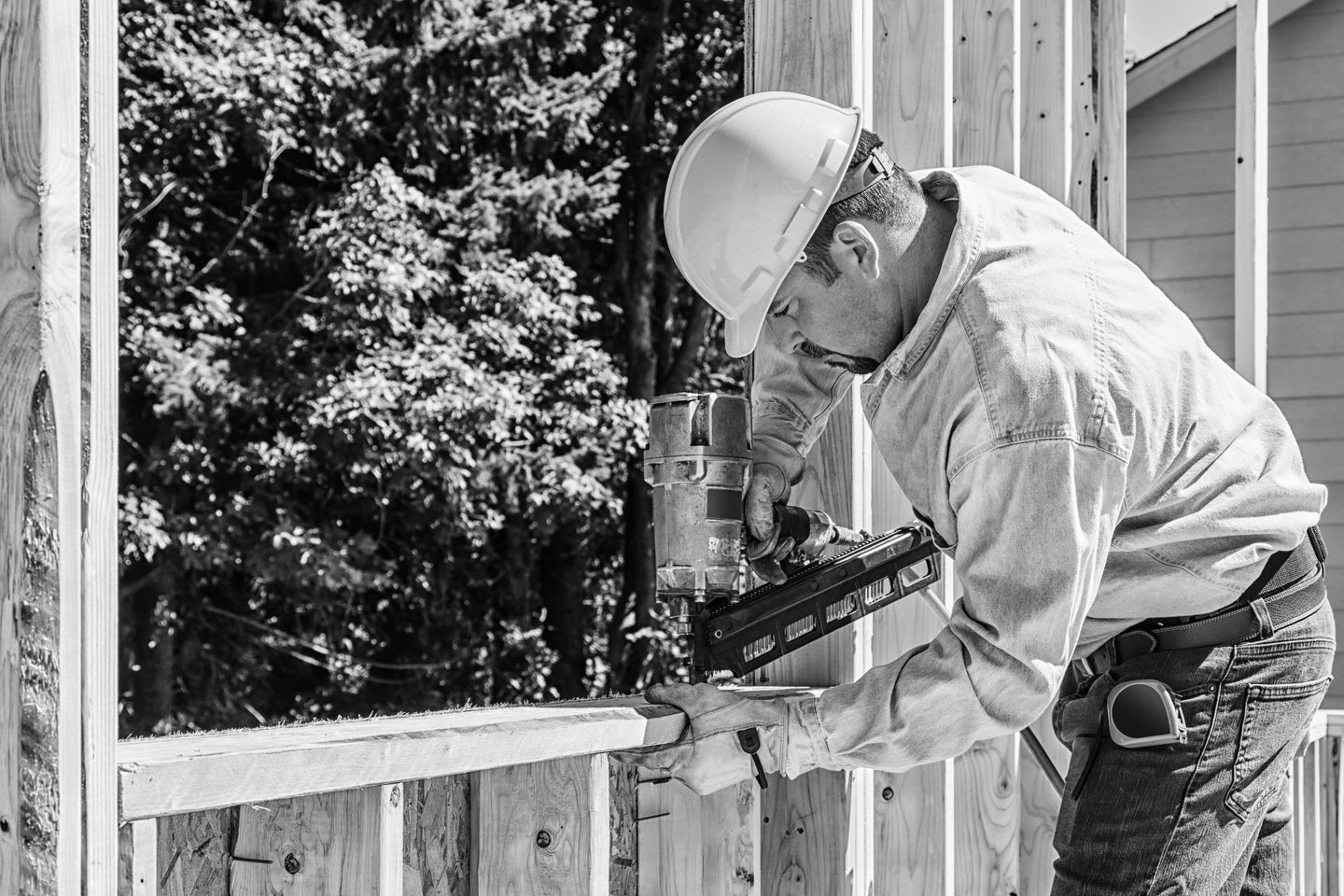 Construction worker with nail gun framing window opening on home building job site